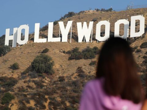 Mulher olha para letreiro de Hollywood, em Los Angeles